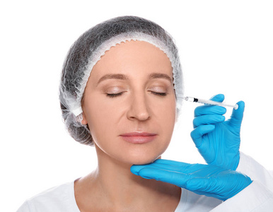 成熟的女人得到面部注射的白色背景。整容手术理念