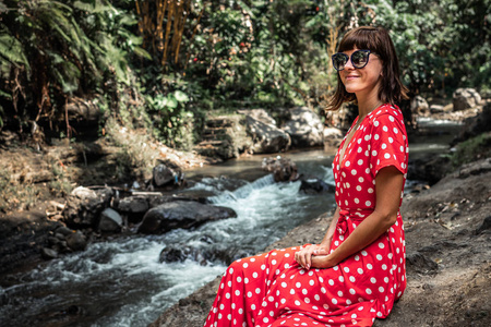 在印度尼西亚巴厘岛热带雨林深处的一条山河上摆姿势的年轻女子