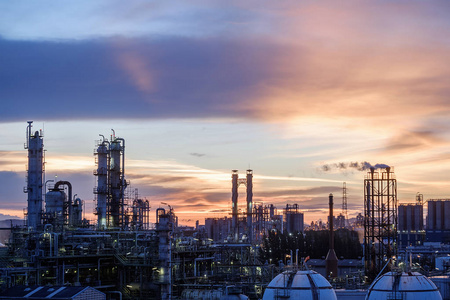 石油天然气精炼厂或石化工业在天日落背景下, 蒸馏塔和烟堆石油工业厂房的制造