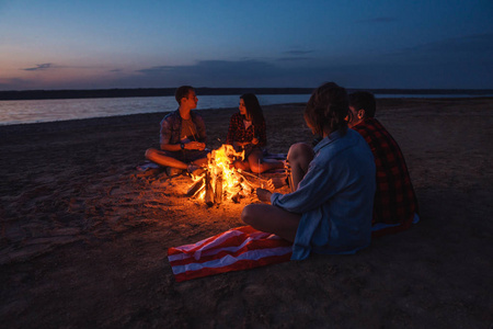 年轻的朋友在海滩上野餐和篝火