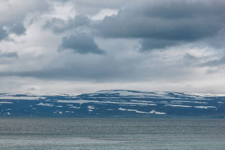 冰岛多云天空下的戏剧性拍摄背景下雪山