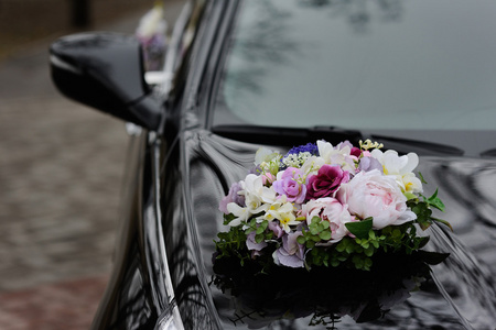 婚礼鲜花的一辆黑色轿车引擎盖上