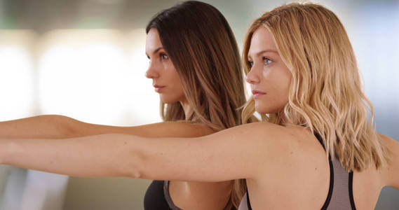 两位漂亮的年轻女士在室内瑜伽工作室练习瑜伽的特写镜头