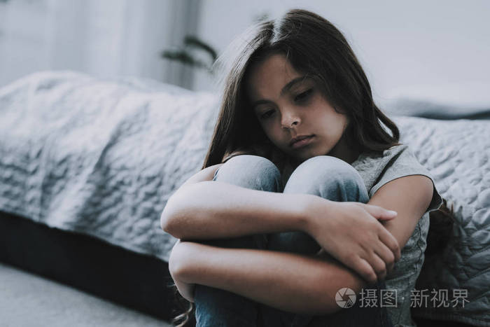 特写肖像皱着眉头不愉快的黑发白种孩子坐在床上穿着灰色 t恤保持双手