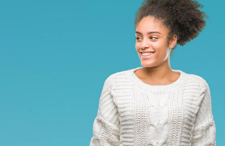 年轻的美国黑人妇女穿着冬季毛衣在孤立的背景看着一边微笑着脸, 自然的表达。笑的自信