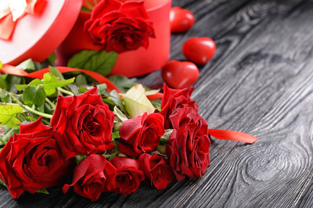 美丽的花束红色玫瑰和礼品盒在木质背景