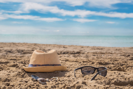 阳光玻璃和阳光帽在沙滩上对抗绿松石般的大海。热带海滩上的旅游和度假概念。海滩上阳光明媚的日子快乐
