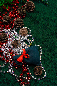 圣诞礼物装饰有绿色的树枝, 松果, 礼品袋红色和银色的珠子花环针织面包。圣诞节或新年绿色背景, 圣诞快乐贺卡