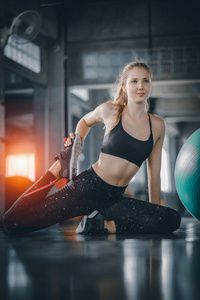 年轻有吸引力的女人健身做运动锻炼与球在健身房。在健身健身俱乐部锻炼后伸展肌肉和放松的妇女