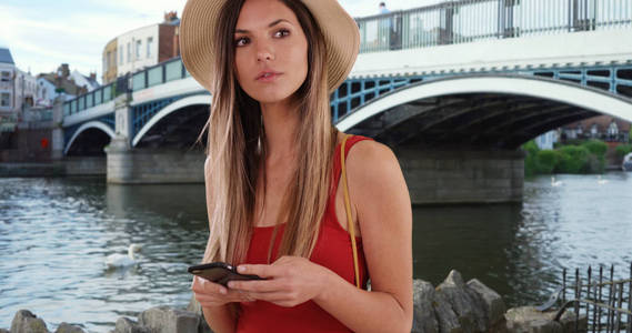 穿着红色上衣的时尚女子使用手机, 在英国温莎四处寻找