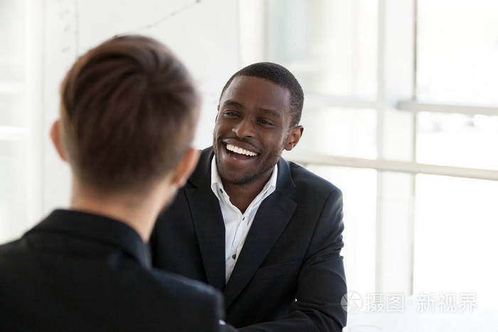 愉快的黑人工作者微笑与同事交谈