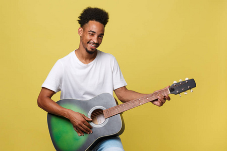 快乐的非洲裔美国音乐家男子摆着吉他, 金色黄色背景