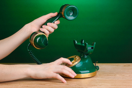 在绿色背景上的木桌上的复古电话拨号
