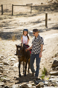 年轻的马孩子骑小马户外满意作为马教练在牛仔看父亲角色