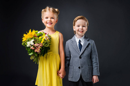 男孩牵手与小女孩与花束的花朵, 孤立的灰色