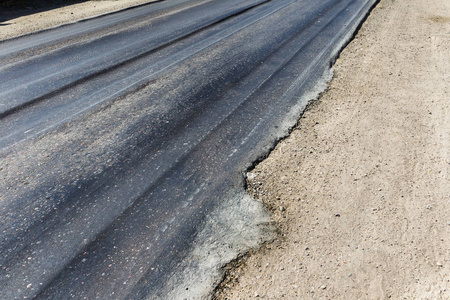 破损的道路, 破损的沥青和坑洞和斑点。非常坏沥青路与大 trenche。公路建设中的严重的沥青生产技术。软沥青从热中融化