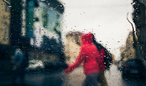 在汽车挡风玻璃上看到雨水滴落的城市道路