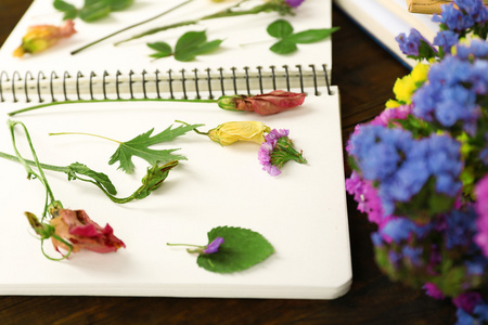 用鲜花和植物放在桌上的笔记本枯竭组成关闭