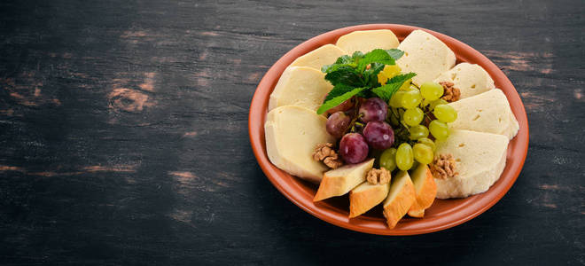 盘子里有奶酪。Brynza 和 Suluguni 奶酪。在旧的木质背景。文本的可用空间。顶部视图