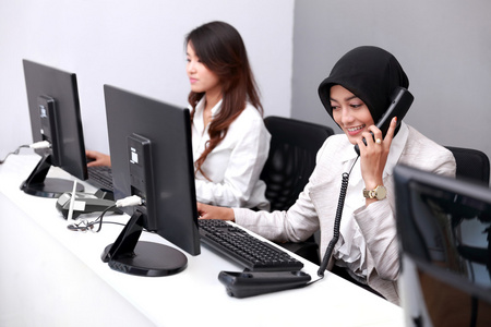年轻女商人工作使用时接听电话