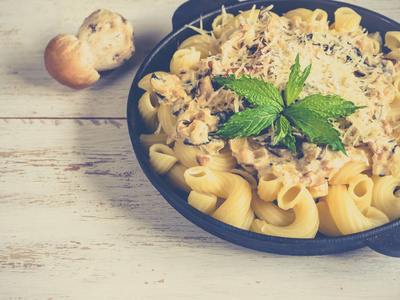 面食 cavatappi 与 cepes 在木桌上的铁锅里