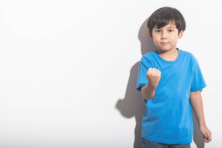 年轻的男孩肖像在白色背景与硬光。穿着蓝色衬衣和琴的混血男孩。力量和力量姿态