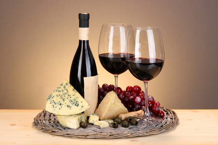 生活依然精致的红酒 奶酪和米色背景上的木桌上的柳条托盘上的葡萄