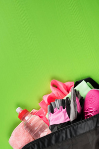 在一个绿色的背景, 一组女性运动的东西粉红色的颜色在一个开放的袋子与一瓶水