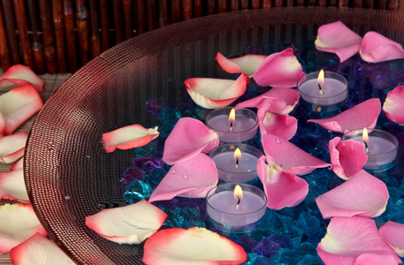 玫瑰花瓣和木制背景上的木桌上花瓶里的水中的蜡烛