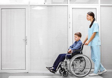 年轻女医生照顾小男孩在轮椅室内