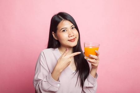 年轻的亚洲妇女在粉红色背景点橙汁
