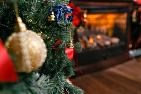 装饰圣诞树, 在前景球上的树枝和弓。带壁炉的经典公寓。圣诞节晚上。圣诞树上的礼物