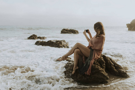 在海滩上用手机拍照的女人