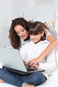 母亲和孩子在家里与便携式计算机的特写