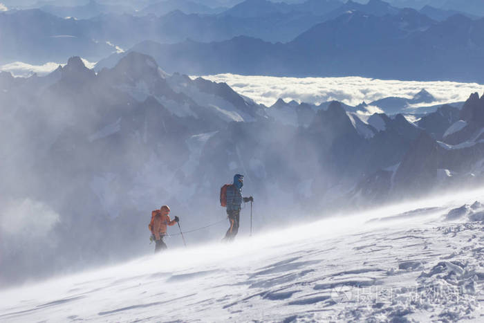 被装备的攀登者上升由雪的倾斜与攀登绳索山顶在雪山高山.