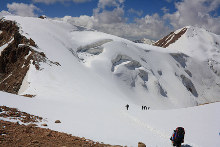 一群登山者沿着冰川漫步, 在一个阳光明媚的早晨征服山口。哈萨克斯坦天山