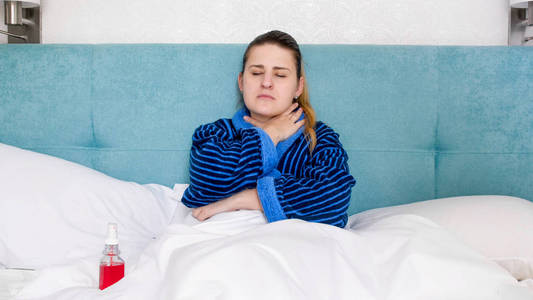 患有流感和喉咙痛的患病妇女的肖像牵手在颈部疼痛