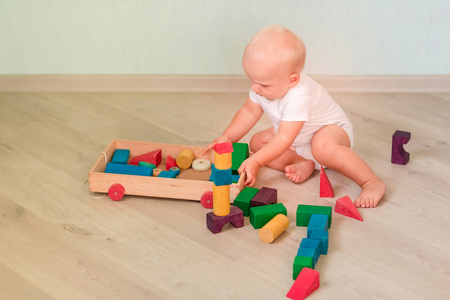 可爱的小宝宝玩彩色木块在房间里。早期发展概念