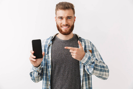 一个自信的年轻胡子男子的肖像站在白色的孤立, 显示空白屏幕移动电话, 指着手指