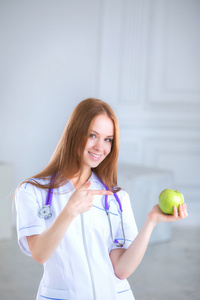 医生抱着一个绿色的苹果。健康食品的概念