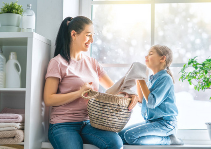 年轻漂亮的女人和孩子女孩小帮手中能开心，并微笑着做在家里洗衣