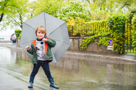 室外肖像的可爱小金发男孩雨下的伞