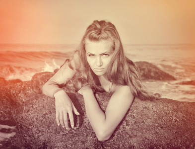一个漂亮的女孩在海边石头上的肖像
