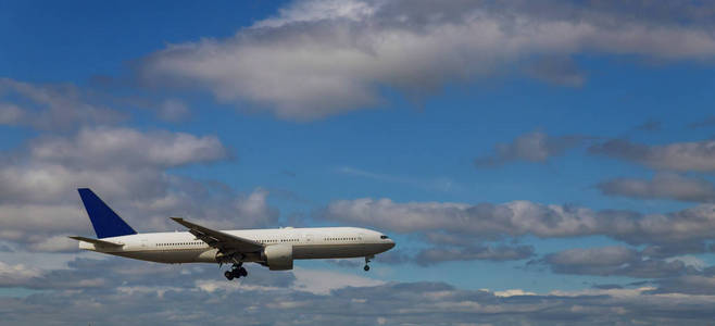 天空中的白色客机降落在白色蓬松的云层背景下