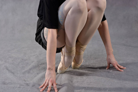 在灰色背景的尖鞋的芭蕾舞演员的脚特写镜头。芭蕾舞经典学校