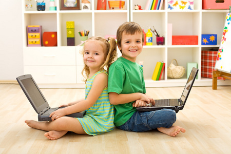 快乐的孩子坐在地板上的笔记本电脑