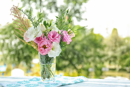 花瓶与美丽的花朵在桌子上反对模糊的背景