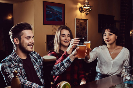 快乐的多种族朋友在酒吧或酒吧里用啤酒敬酒