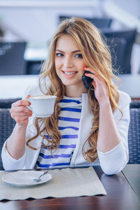 年轻女子在咖啡厅喝咖啡和谈移动电话