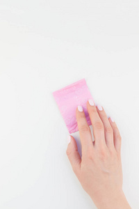 女子手用粉彩指甲抛光持有粉红色的每日卫生巾在白色背景与复制空间隔离。模板为女性美女博客社交媒体。女性保健理念